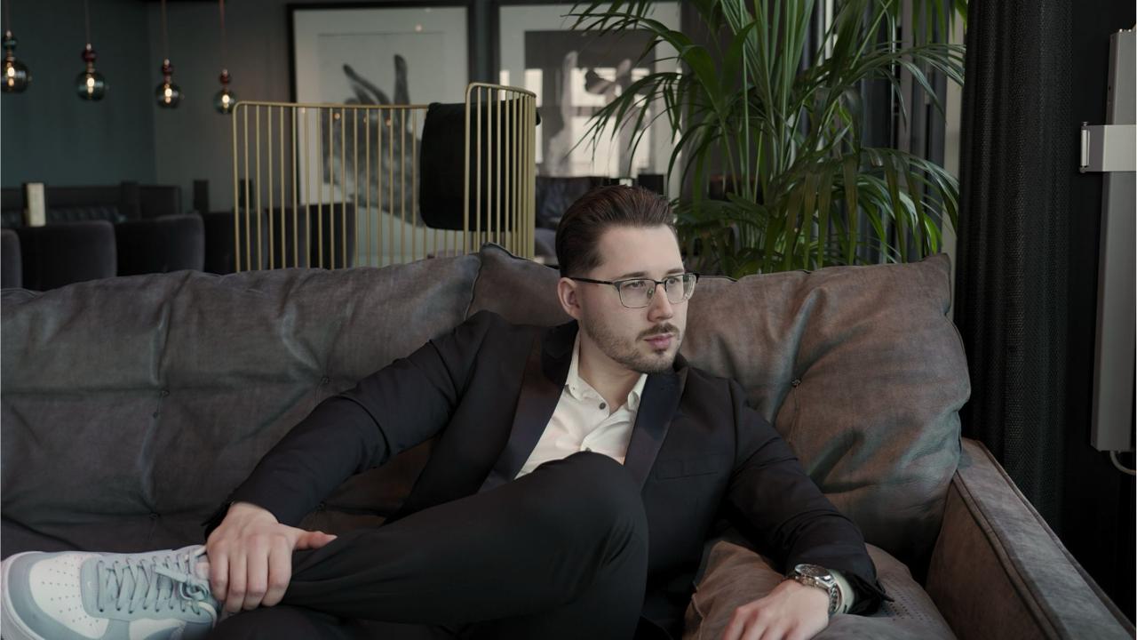 Eugen Riedel sitzt im Anzug entspannt auf einem Sofa in einer Lounge