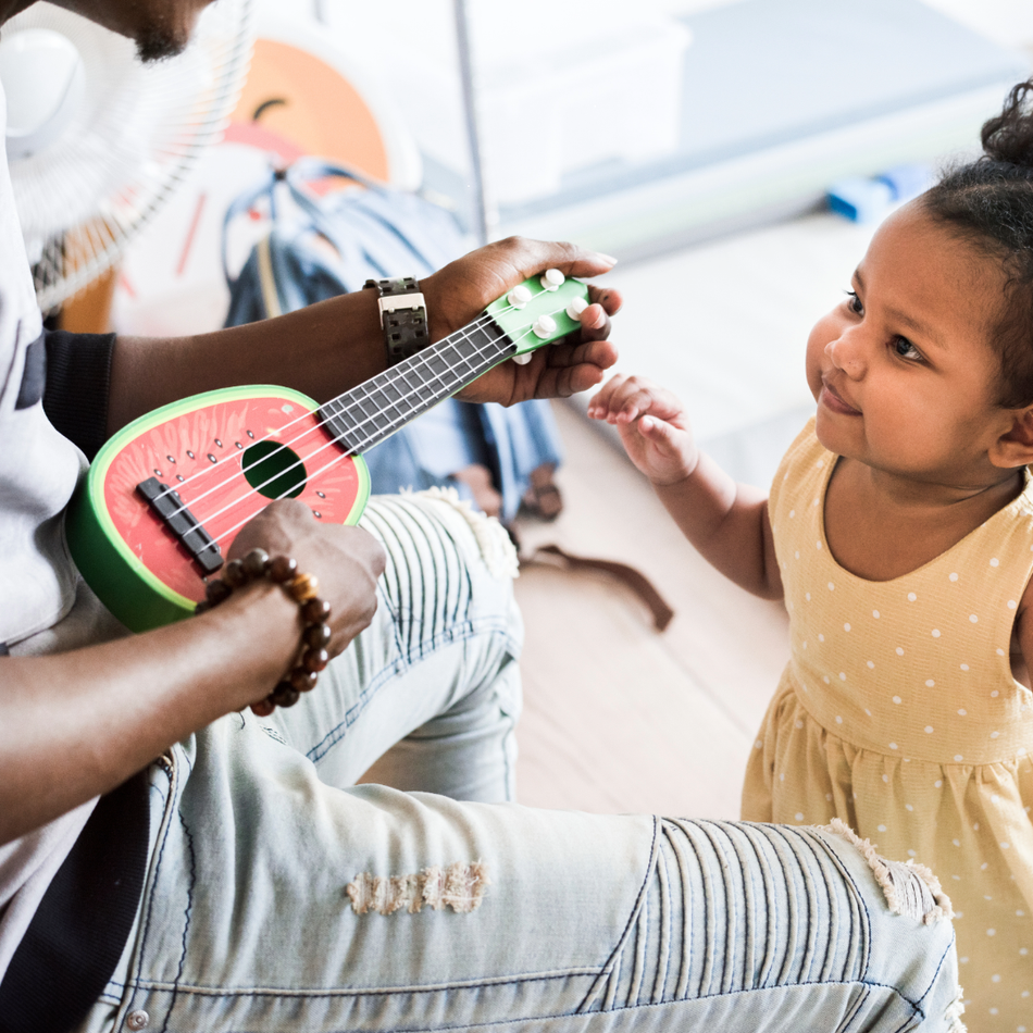 En far synger og spiller ukulele for sin lille jente. 