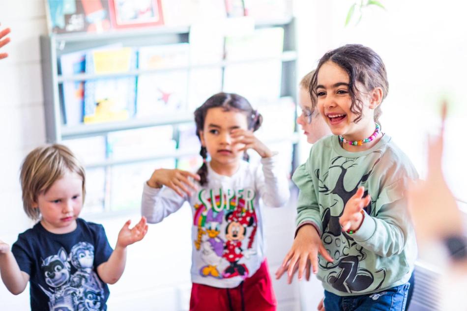 Flere barn danser, synger og ler i samlingsstund i barnehagen