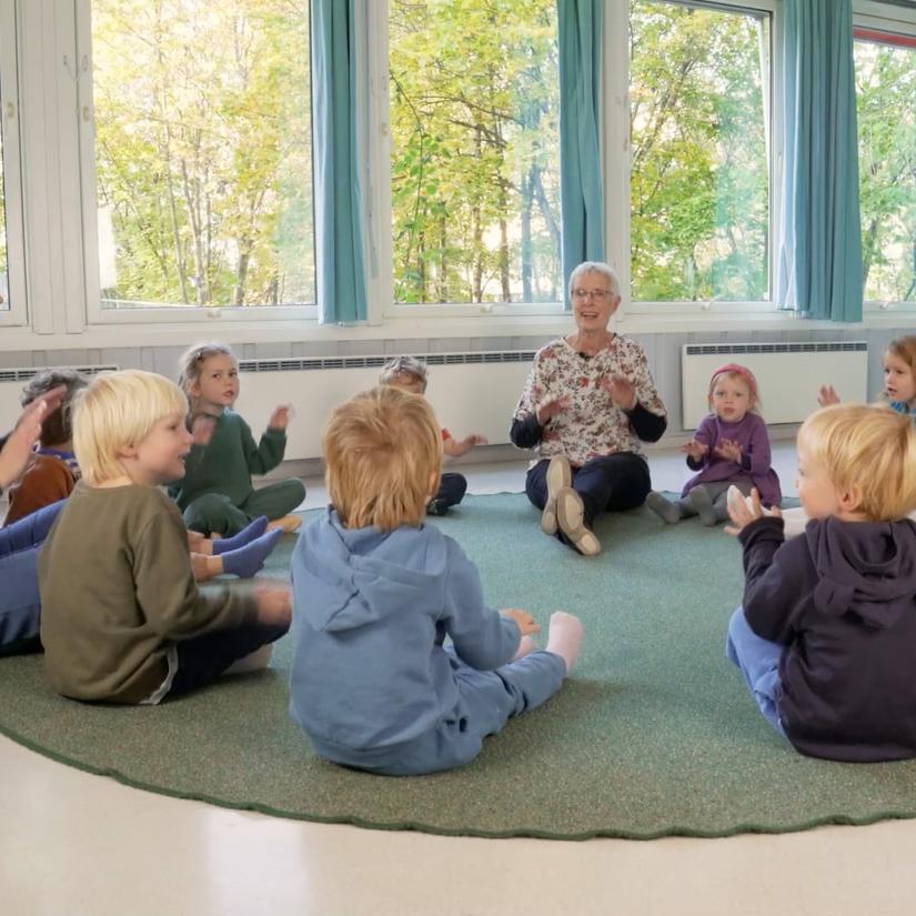 Bilde av barn i sangstund sammen med Bente Bogen og en ansatt.