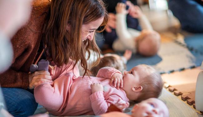 mor titter ned på sin baby som ligger på gulvet