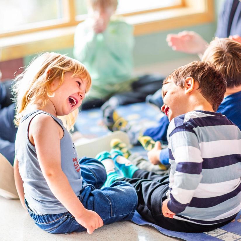 Bilde av en jente og en gutt som ser på hverandre og ler i samlingsstund