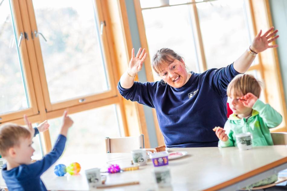 En ansatt i barnehage synger med barna til måltidet