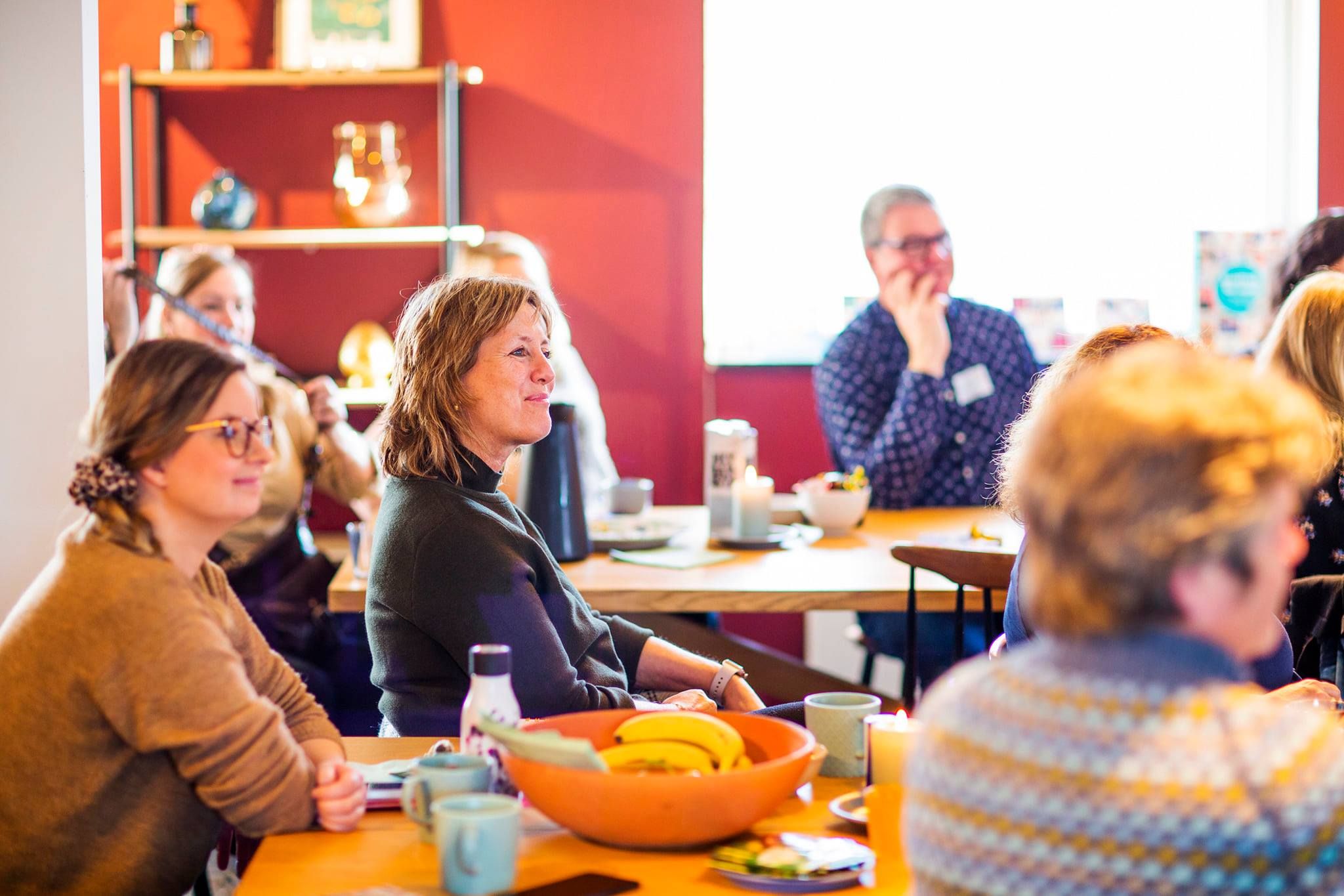 Bildet viser en gruppe voksne som sitter rundt et bord og snakker