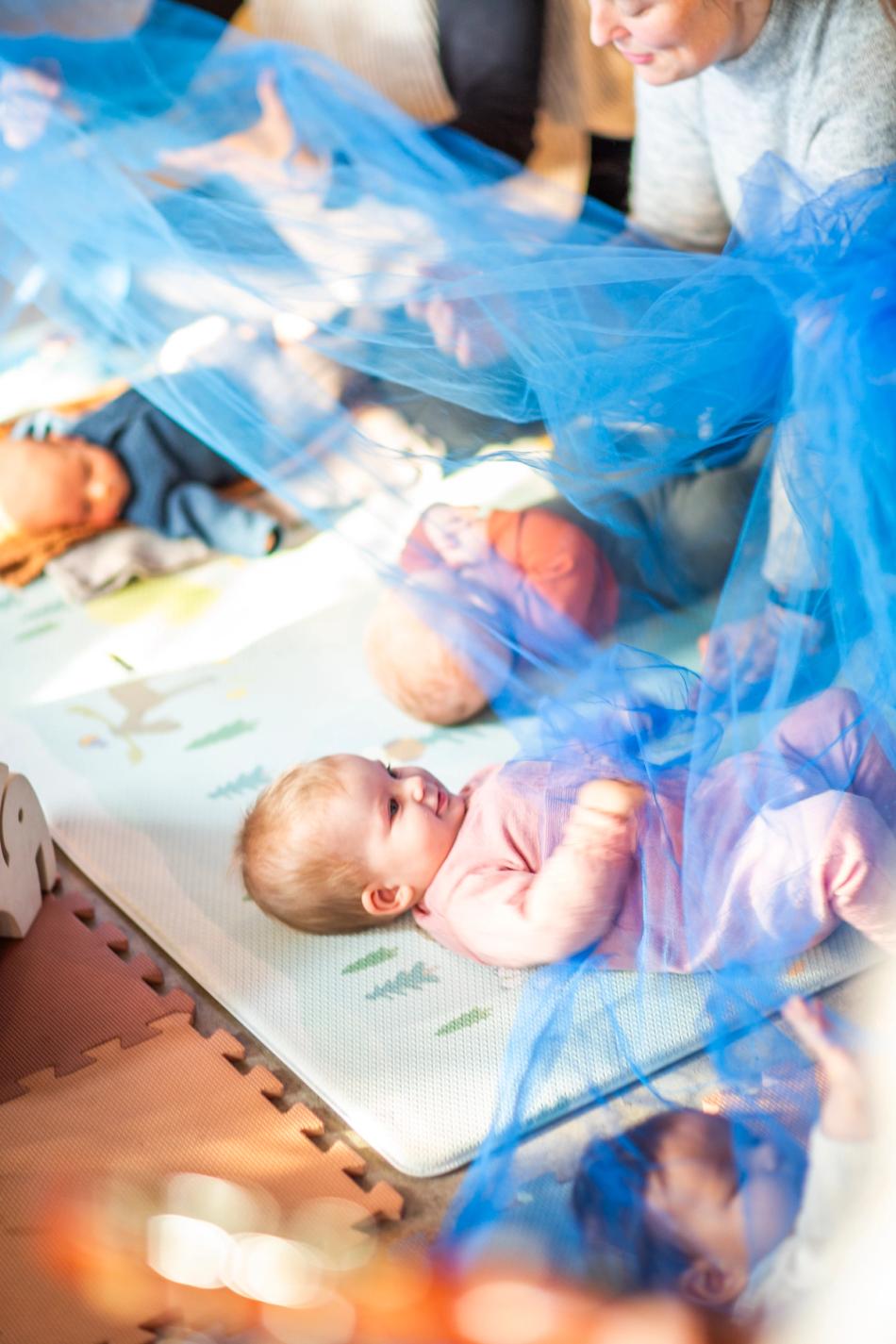 Mothers are singing to their babies lying under a schiffon scarf. Photo: Krafttak for sang
