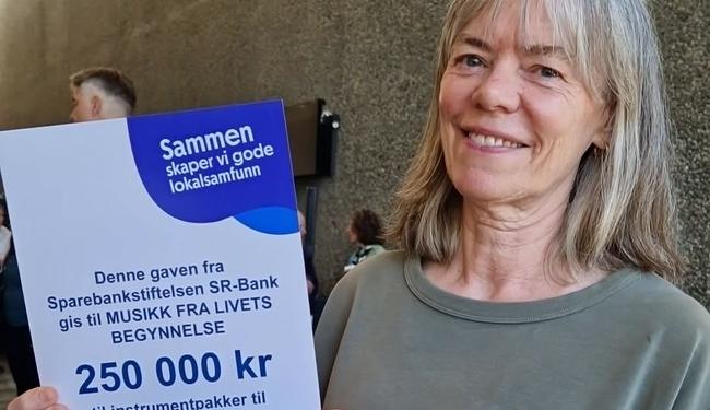 Bilde av daglig leder som viser frem diplomet fra Sparebankstiftelsen