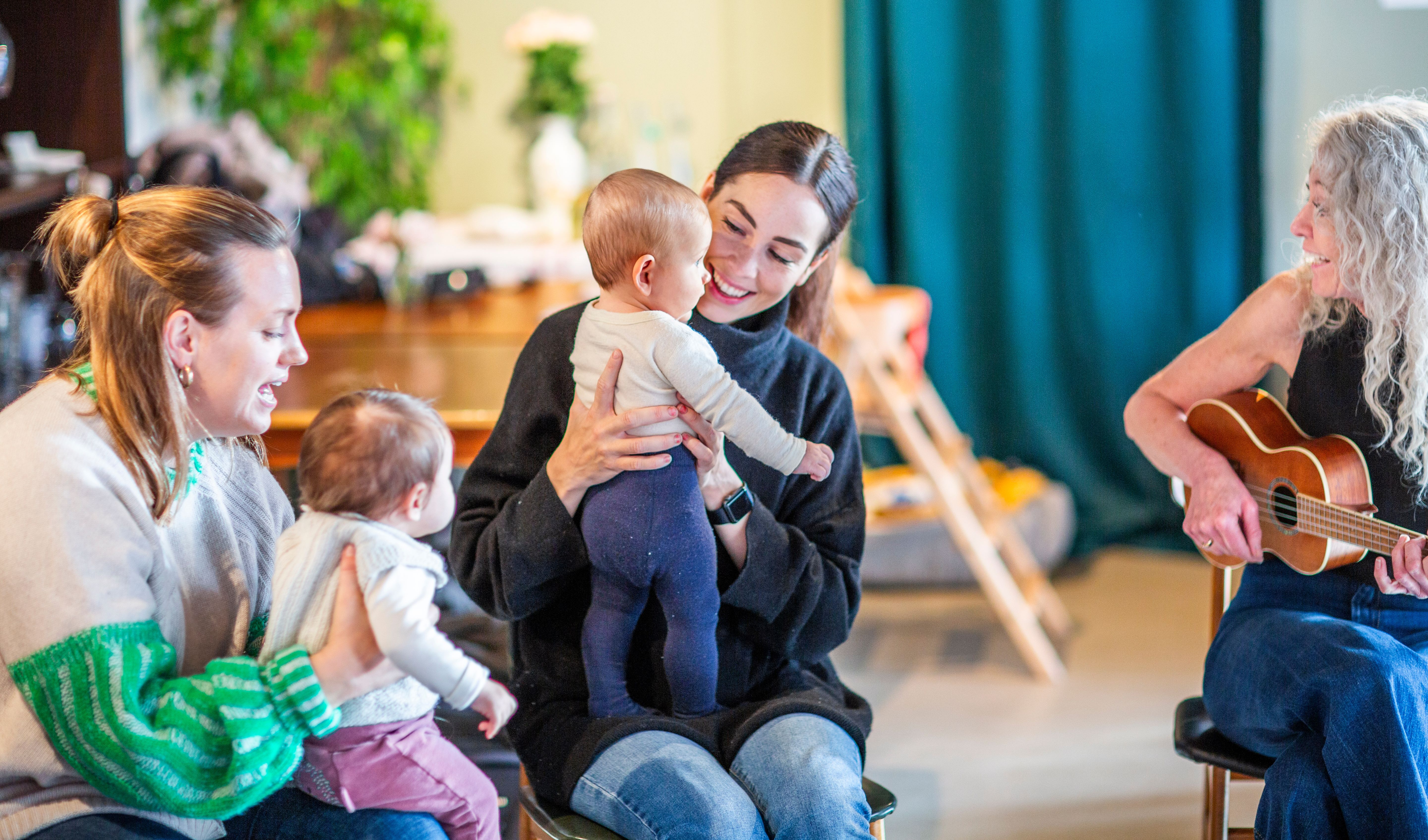 Bilde av en musikkpedagog som synger sammen med to barn og deres mødre