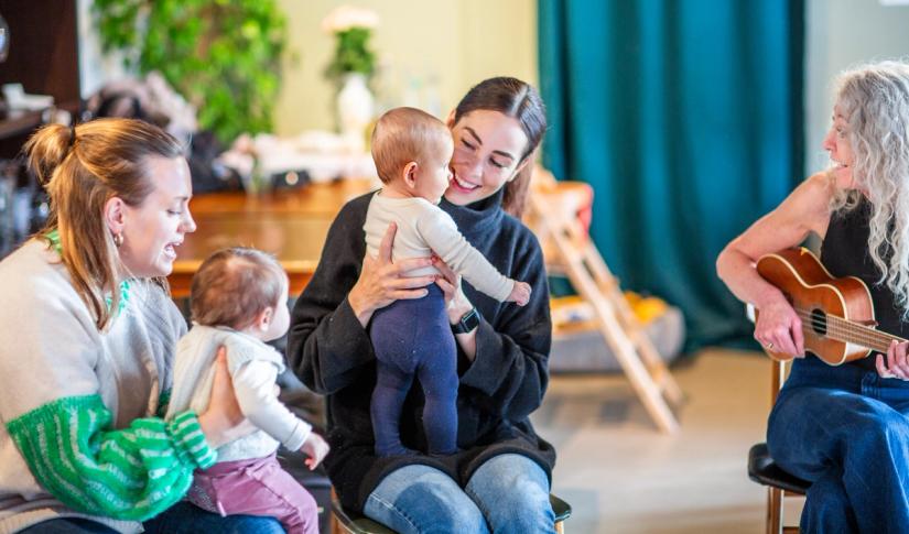 Vi ser to mødre med sine barn sammen med en musikkpedagog. Foto: Krafttak for sang
