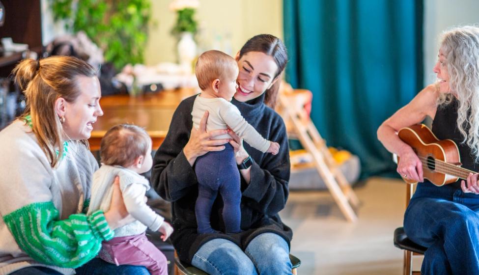 Vi ser to mødre med sine barn sammen med en musikkpedagog. Foto: Krafttak for sang