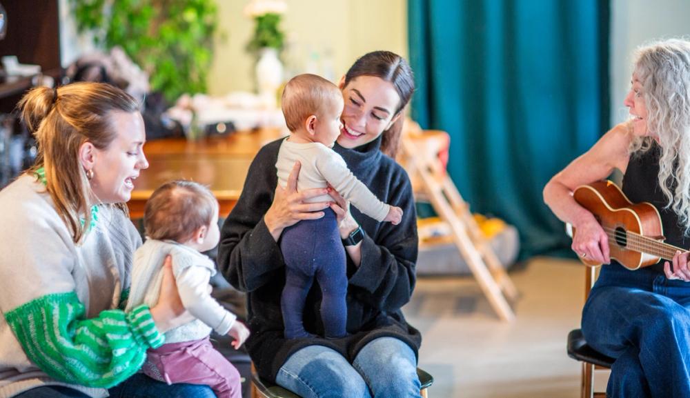 Vi ser to mødre med sine barn sammen med en musikkpedagog. Foto: Krafttak for sang