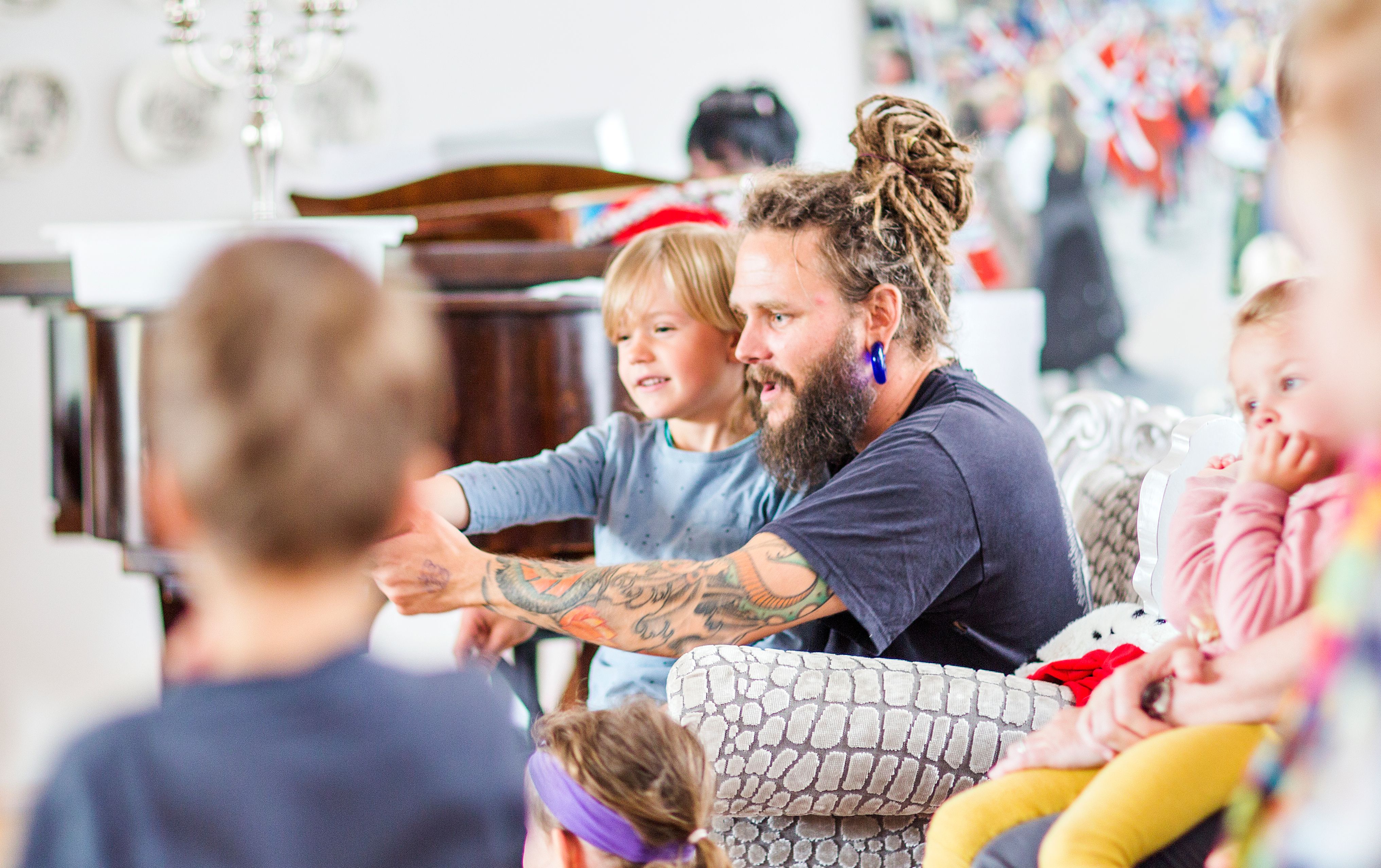 Bilde av en barnehageansatt som sitter i en stol med et barn på fanget. Foto: Krafttak for sang