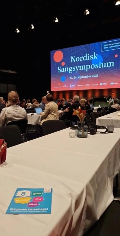 Bilde av en brosjyre som ligger på et bord i salen der Nordisk Sangsymposium ble holdt