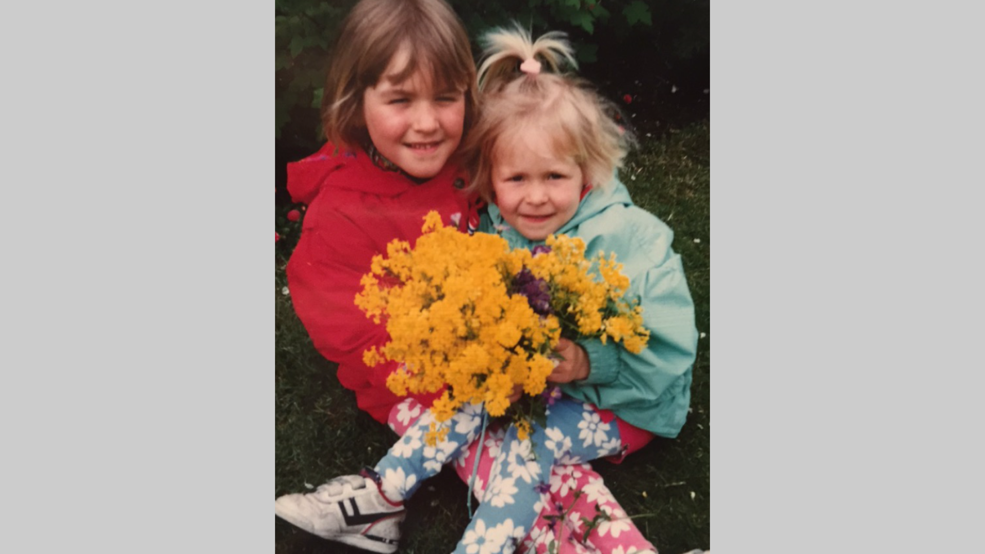 Bilde av to jenter som sitter sammen med en stor blomsterbukett. 