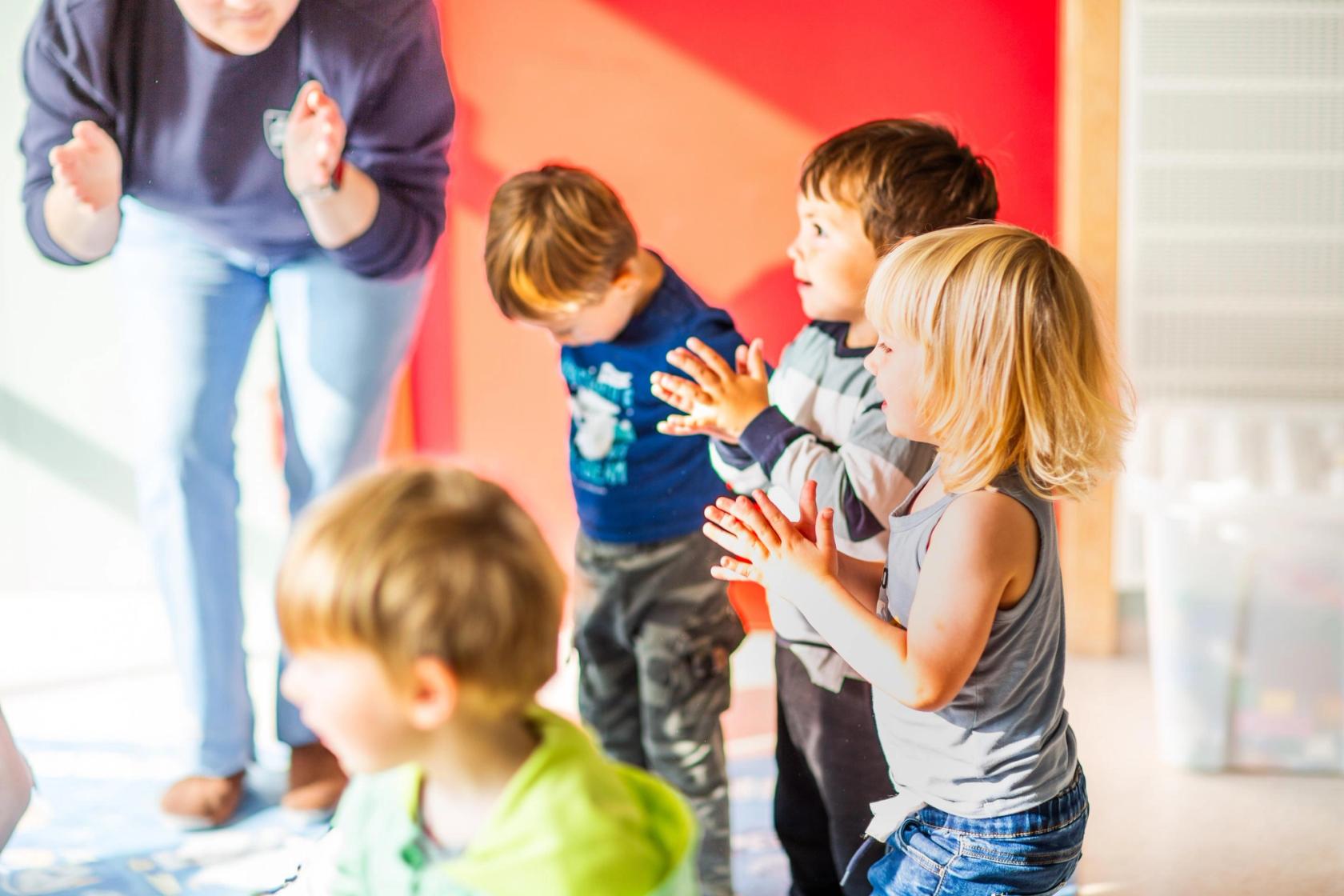 Barn fra en Syngende barnehage synger med en ansatt som sitter i midten og leder an. Foto: Krafttak for sang