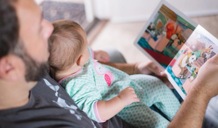 Bilde av en far som leser bok med sin baby