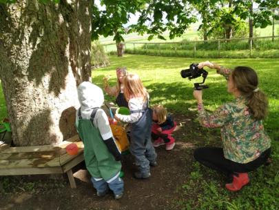 Bilde av fotograf Hilda Nyfløt som filmer barn under innspillingen av dokumentarfilmen En Syngende barnehage