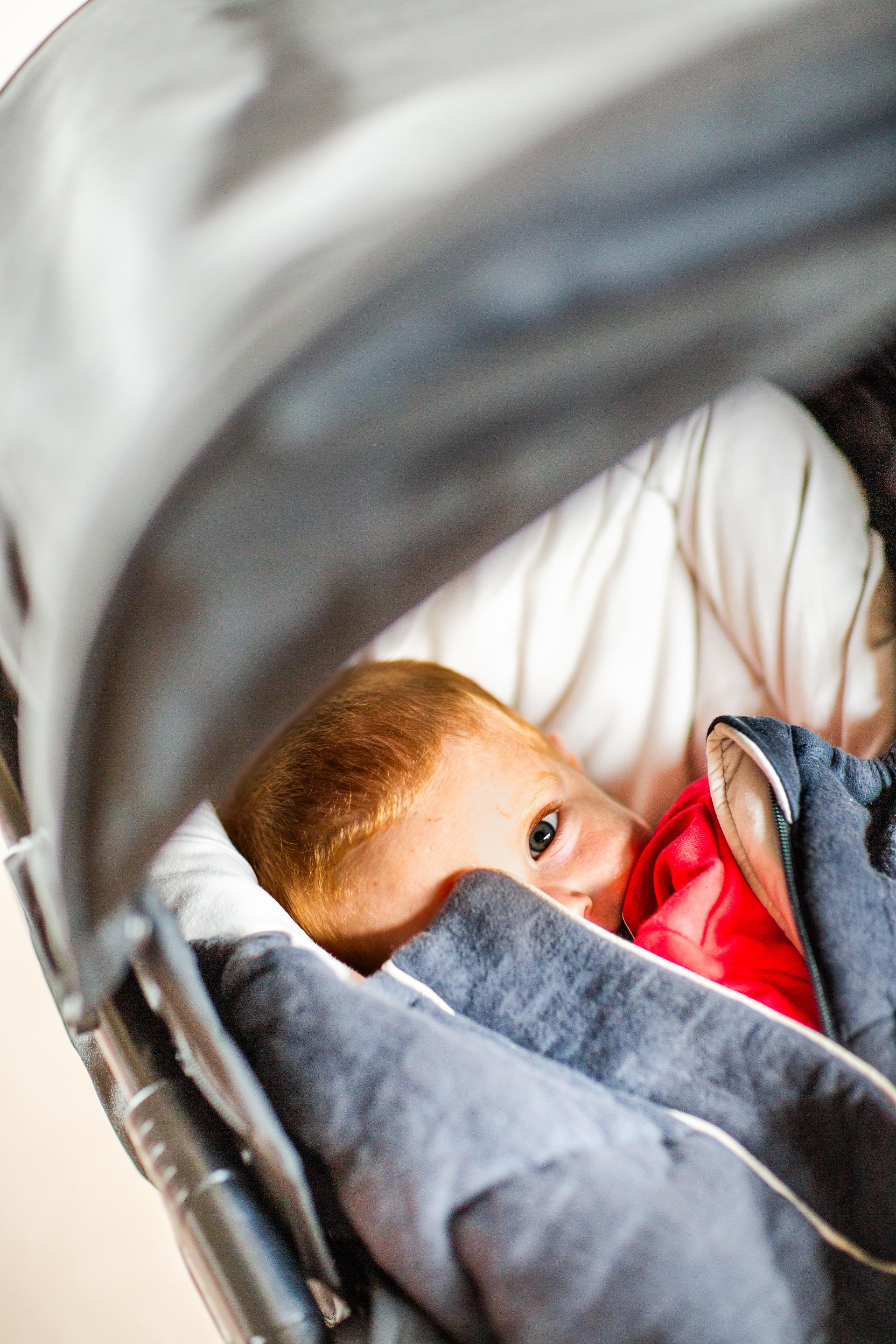 Barn ligger i vogna og ser søvnig ut.