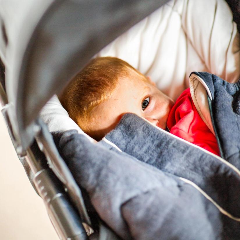 Barn ligger i vogna og ser søvnig ut.
