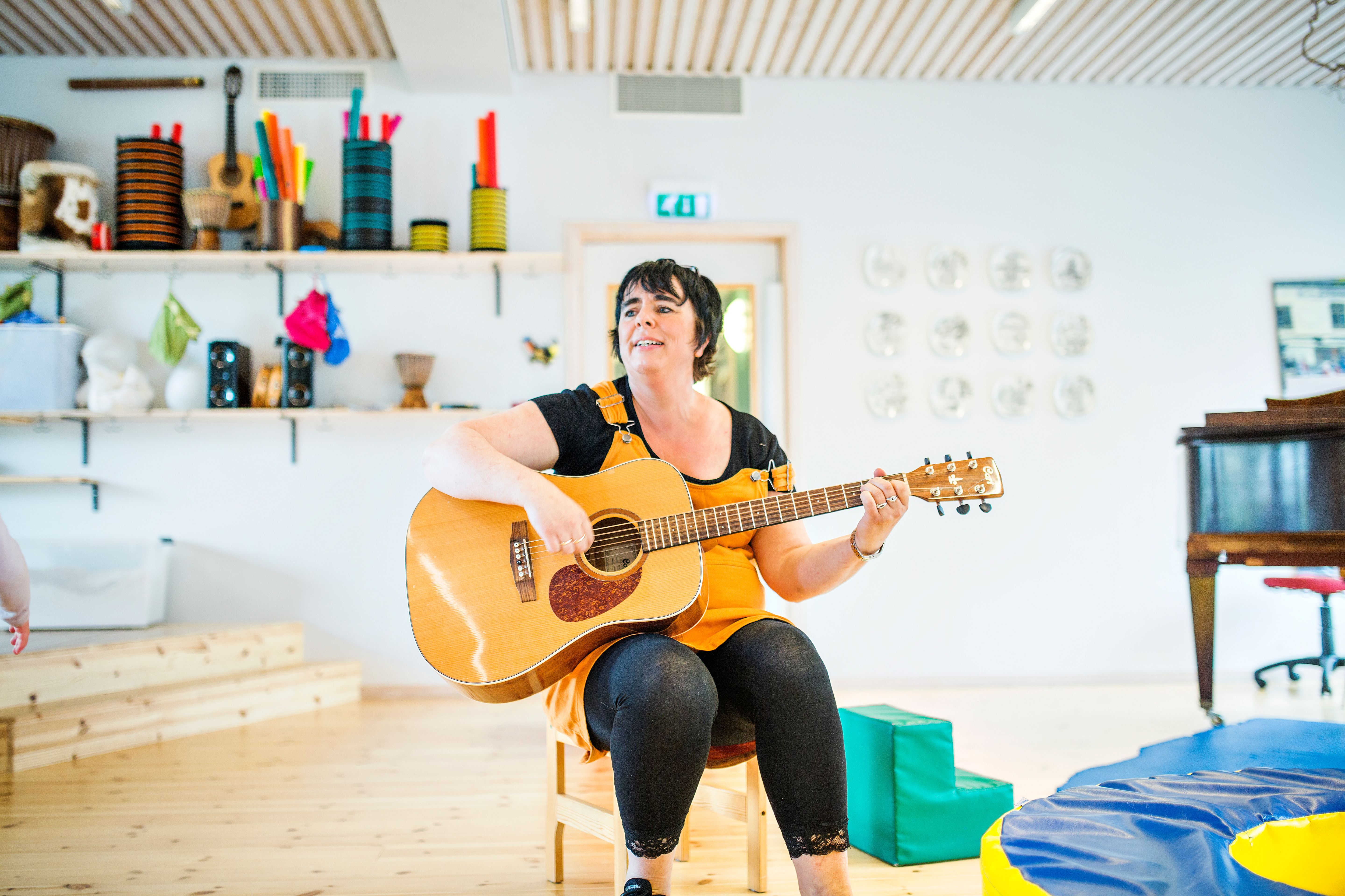 Bilde av en barnehageansatt som spiller gitar. Foto: Krafttak for sang