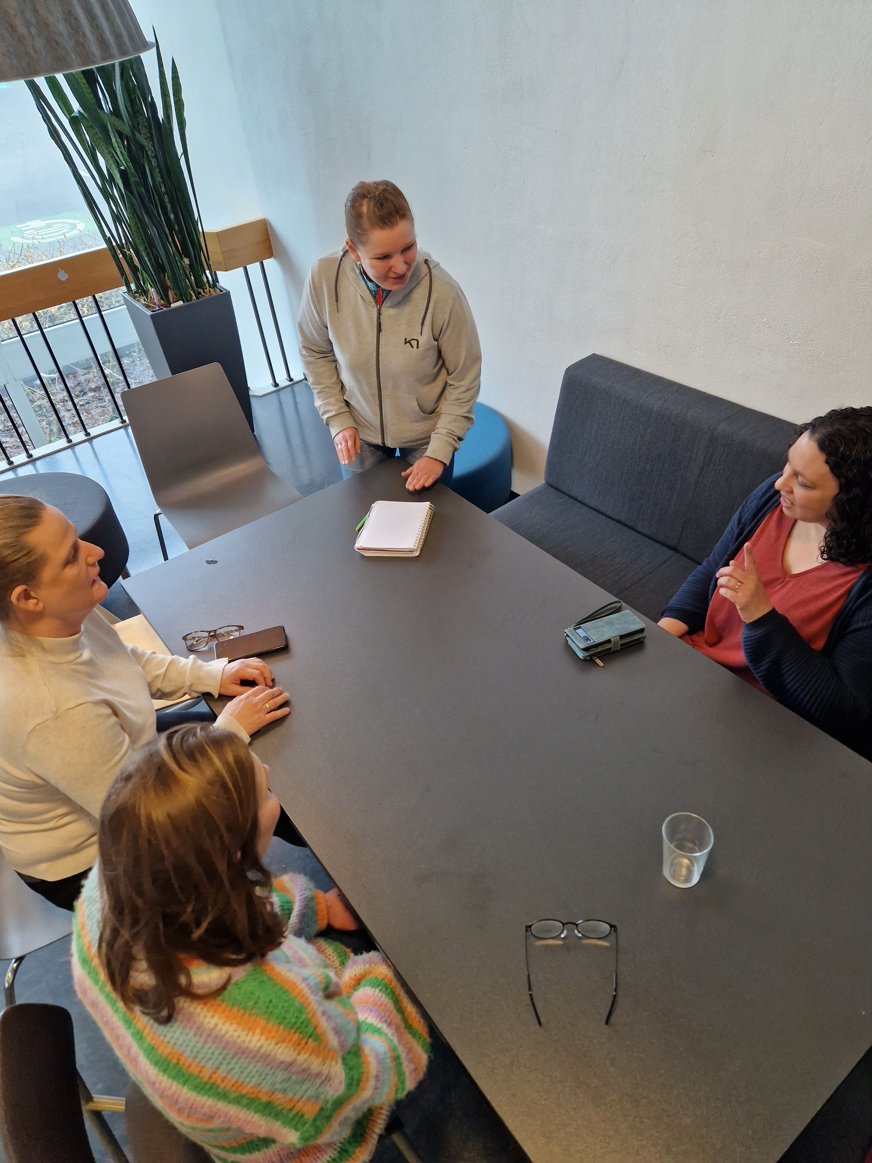 Vi ser fem damer som sitter rundt et bord og gjør gruppearbeid på kurs. 