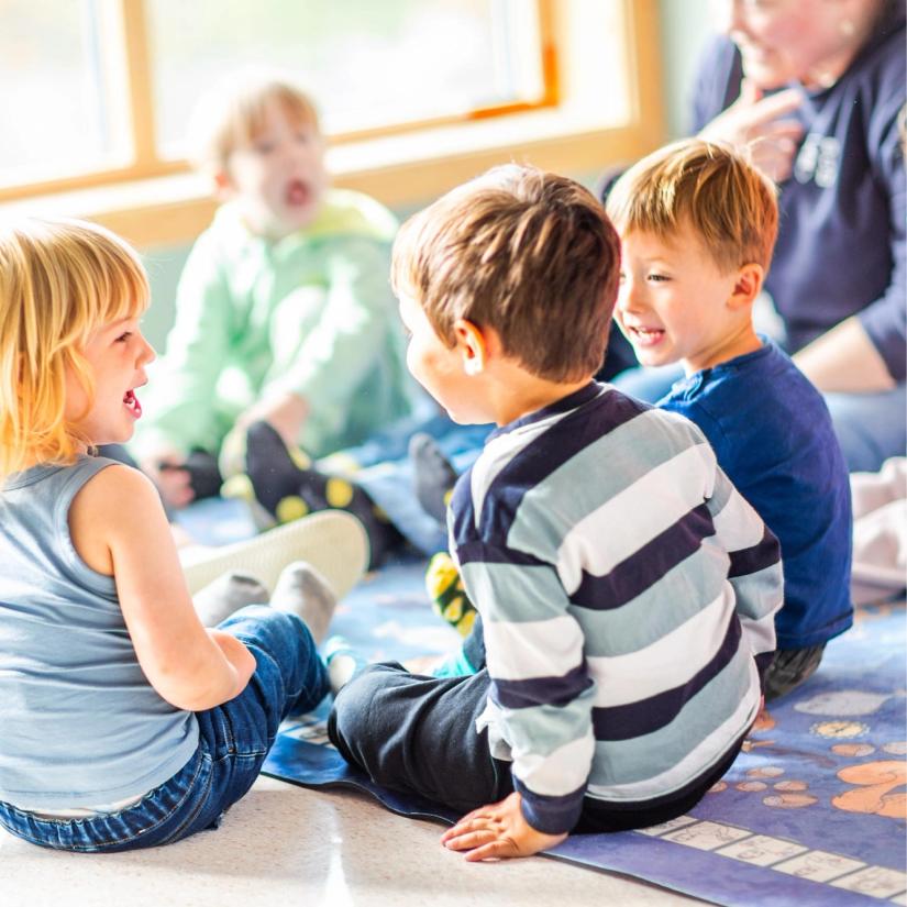 Barn synger sammen og ler i samlingsstund.