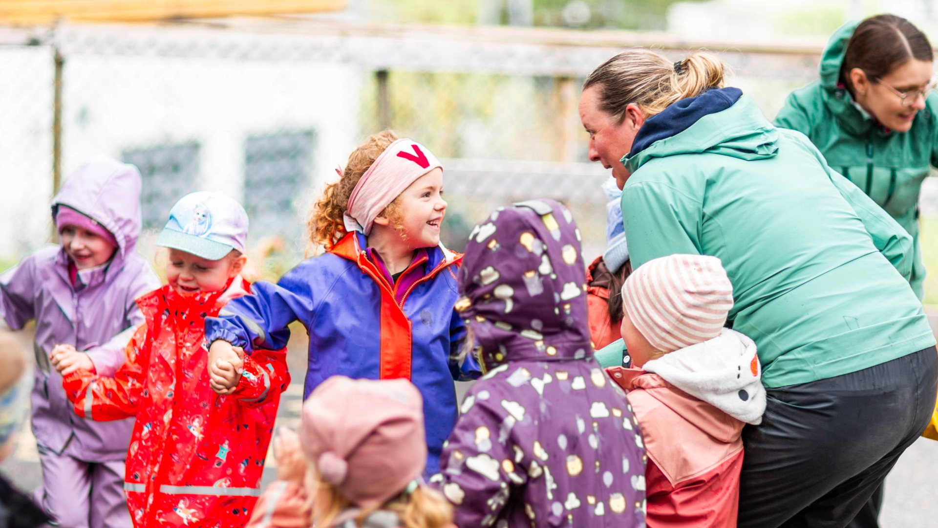 Bilde av barn og ansatte i en barnehage som synger og leker ute. 