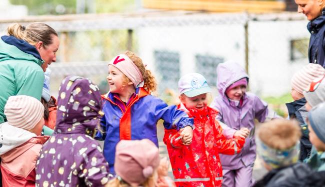 Barn fra en Syngende barnehage synger med en ansatt som sitter i midten og leder an. Foto: Krafttak for sang