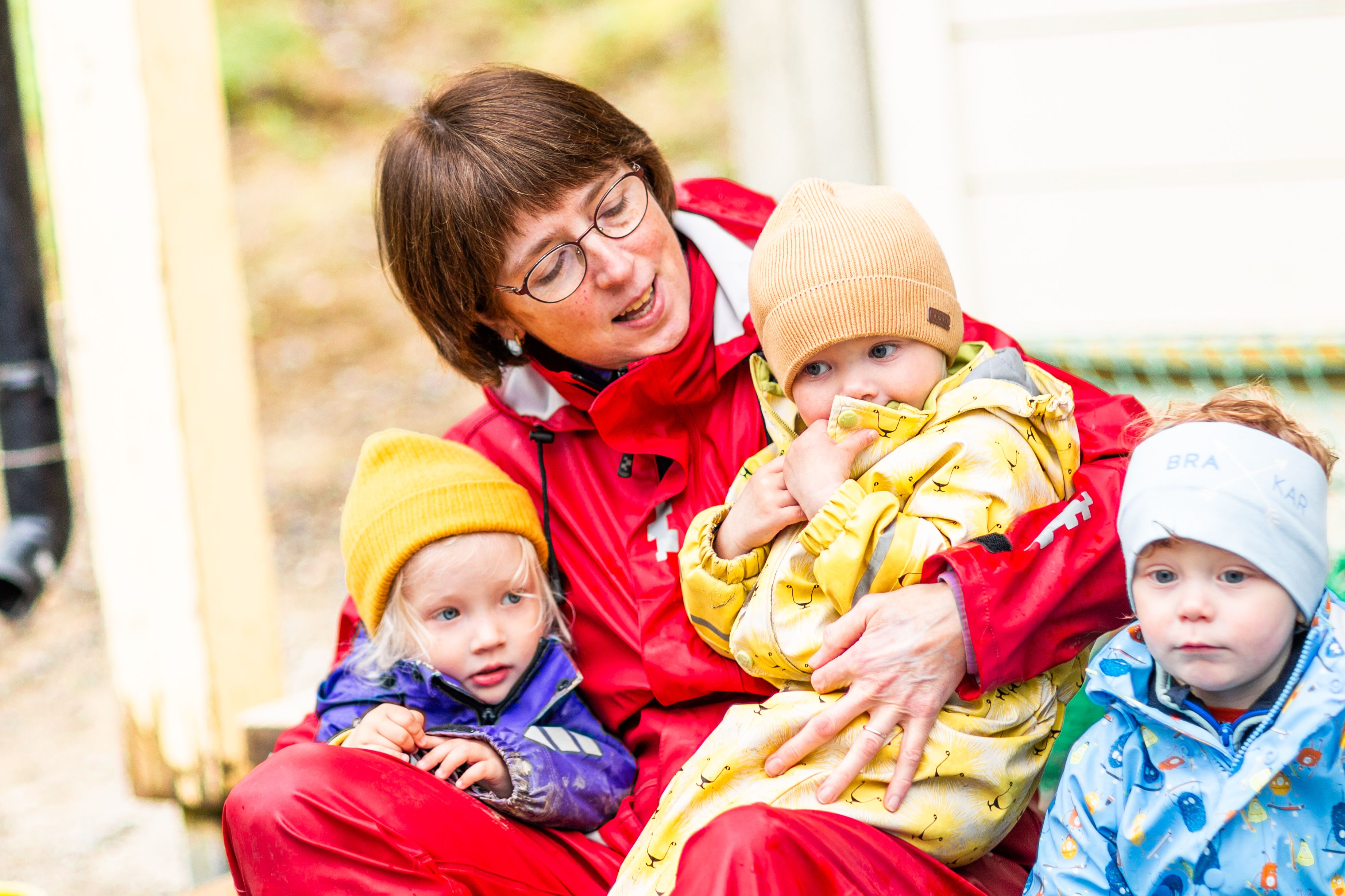 En barnehageansatt sitter med to barn på fanget og synger. Foto: Krafttak for sang