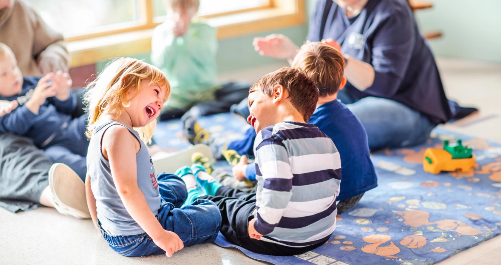 Bilde av to barn som smiler til hverandre i en musikksamling. Foto: Krafttak for sang