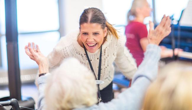 Bilde av en aktivitør som synger sammen med en beboer på en eldreinstitusjon