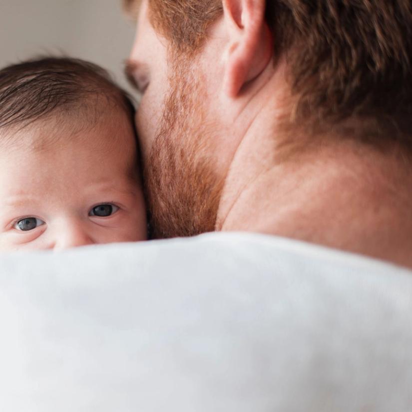Bilde av en baby som hviler på skulderen til far.