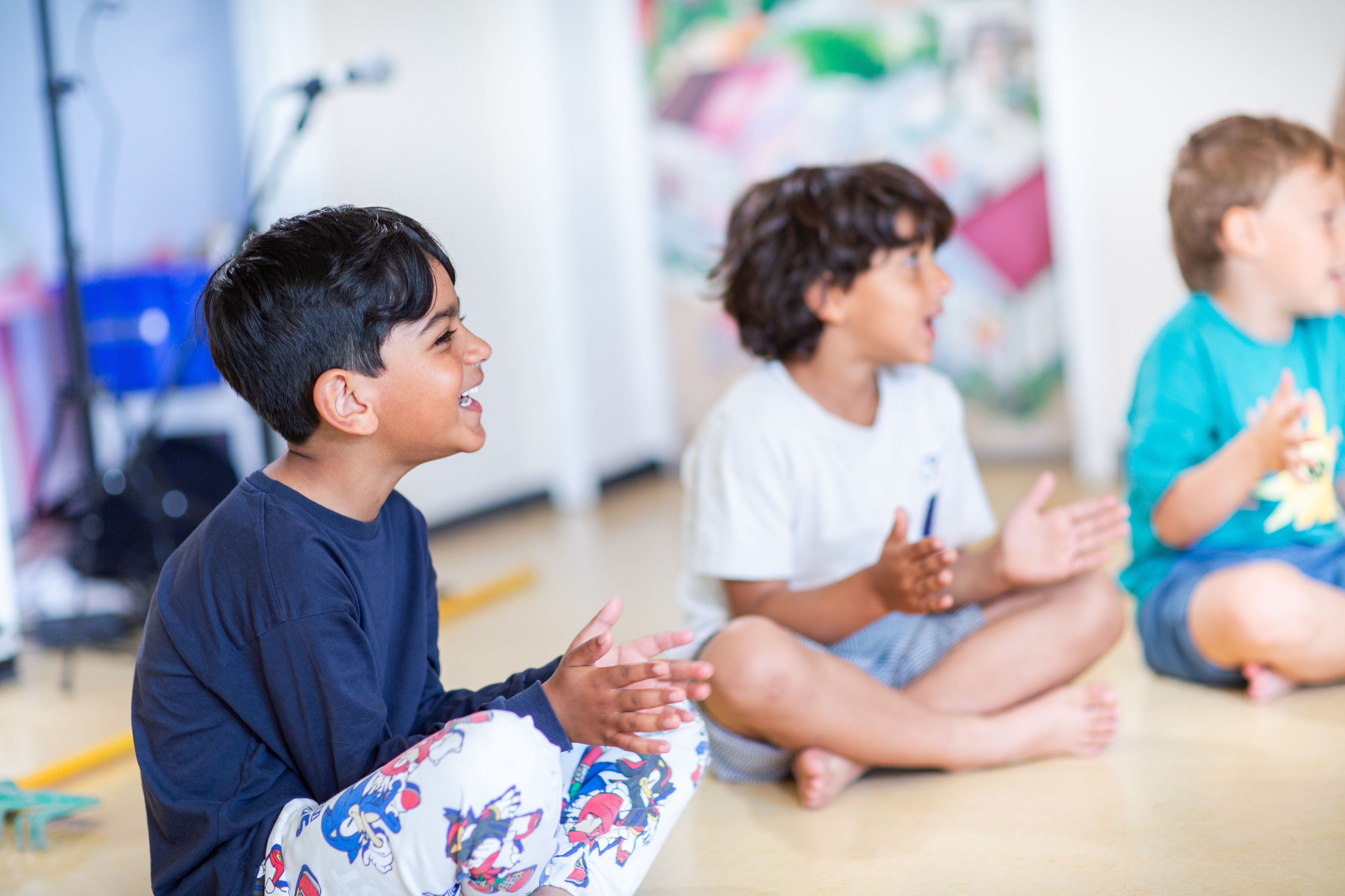 Bilde av tre barn som synger og gjør fingerbevegelser i en samlingsstund