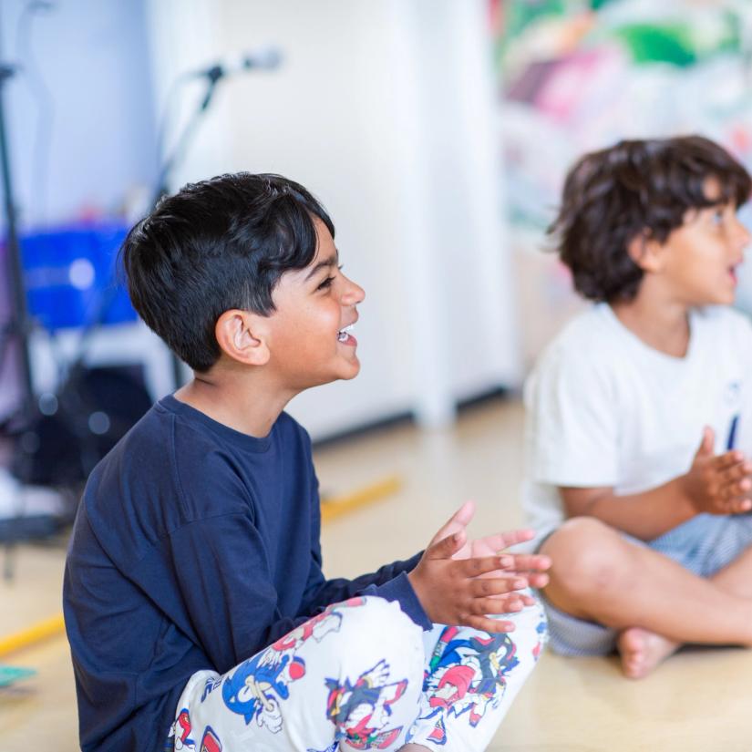 Bilde av tre barn som synger og gjør fingerbevegelser i en samlingsstund