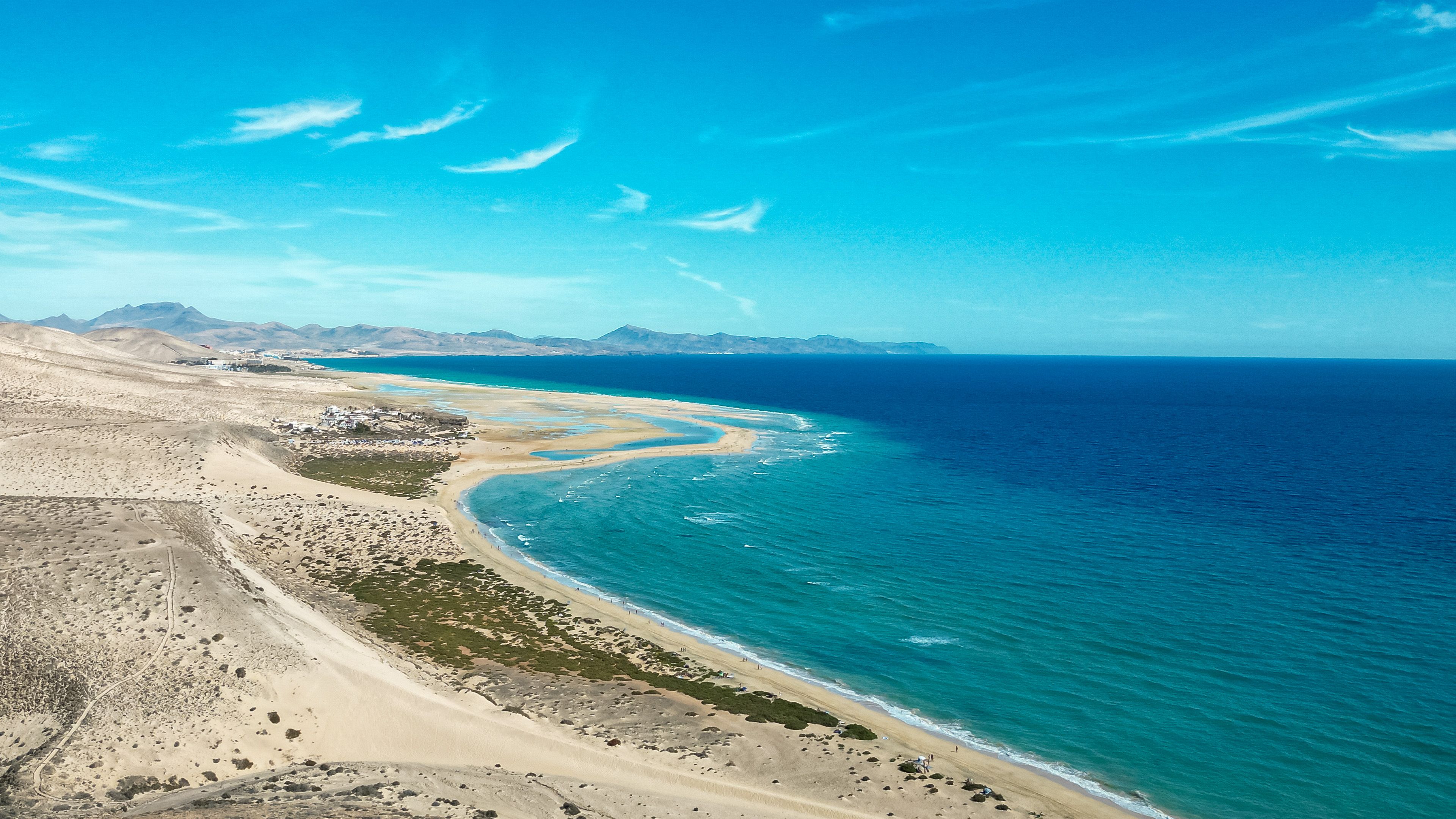 Türkisfarbenes Wasser an der Küste von Fuerteventura mit Blick auf Strand, Berge und Meer