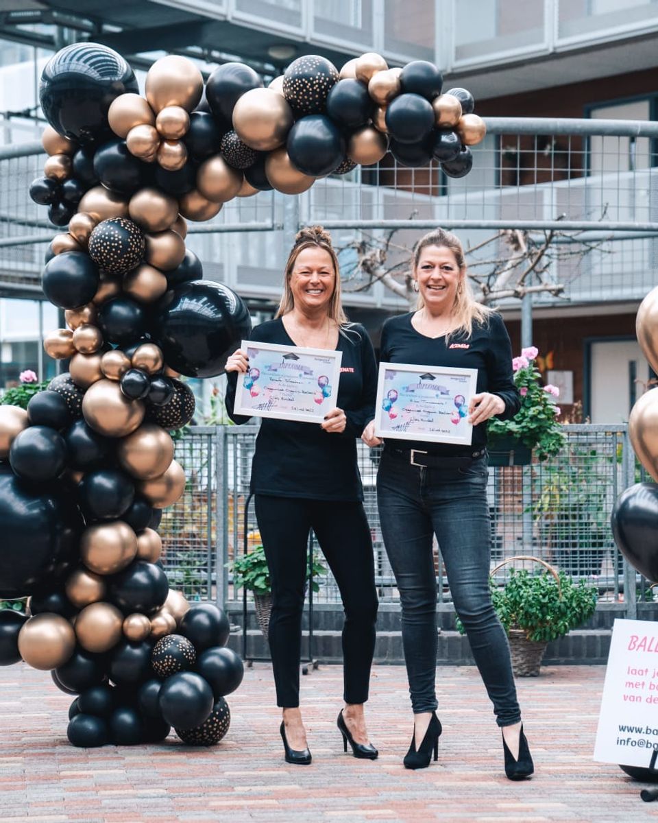 De oprichters van Ballonboog Delft naast een organic ballondecoratie in zwart en goud