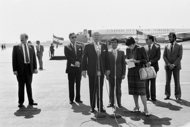 United States Secretary of State George Shultz makes a statement to the media upon arrival at the military airport in Ilopango, El Salvador, January 31, 1984. © Nickelsberg