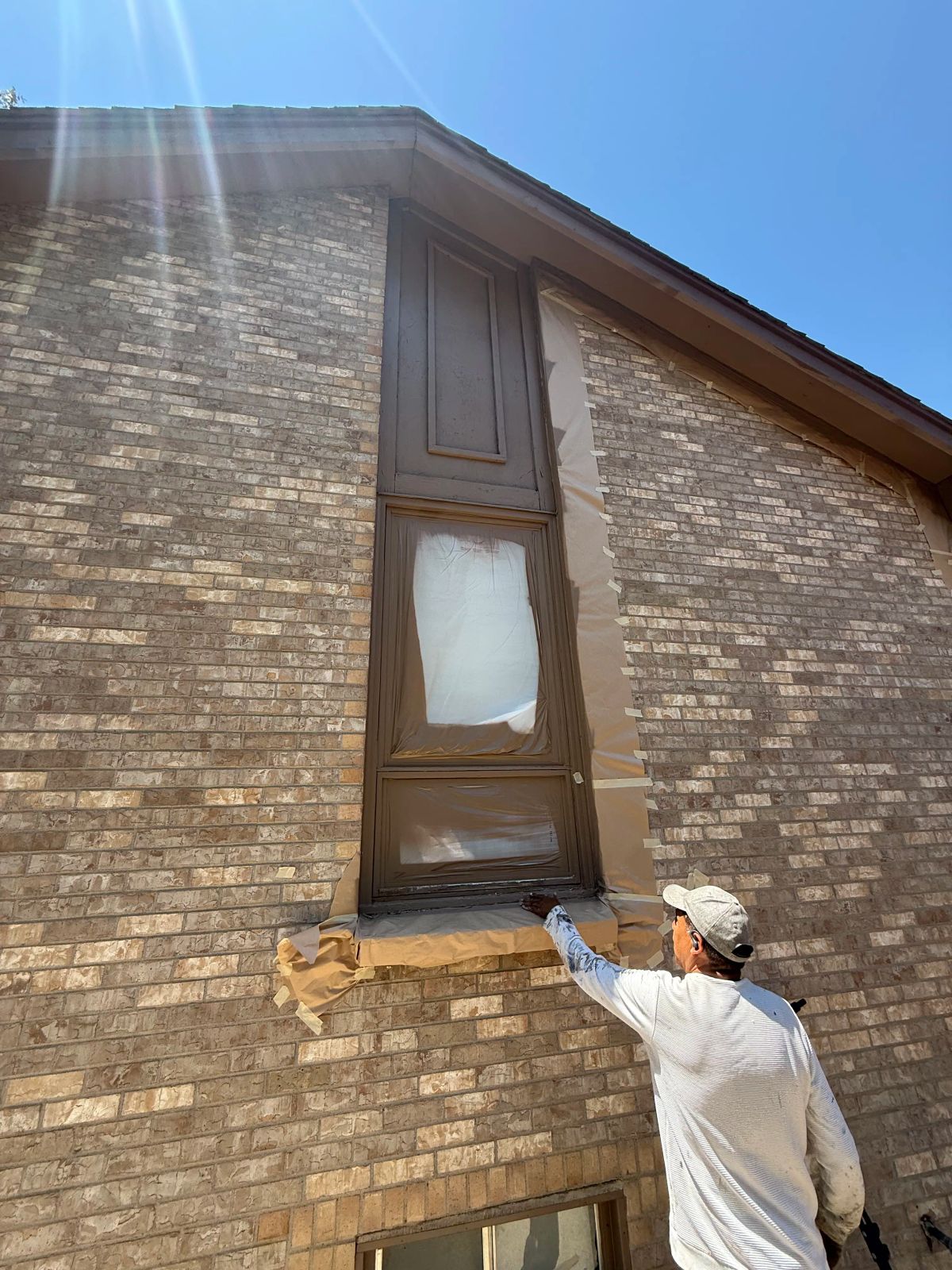 Brick house, window trim taped for painting— Denver