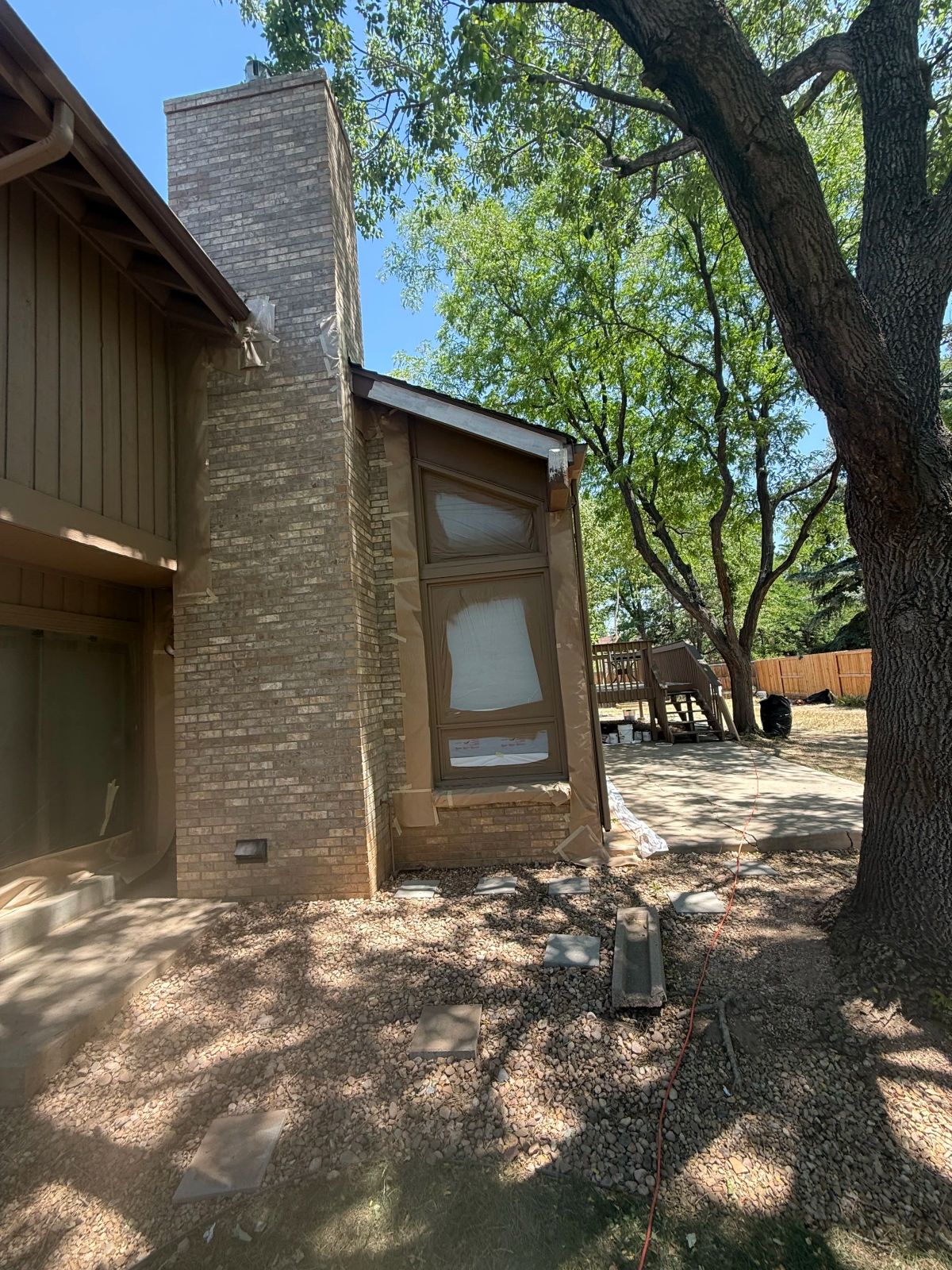 brick chimney, taped window, trees in a Denver home