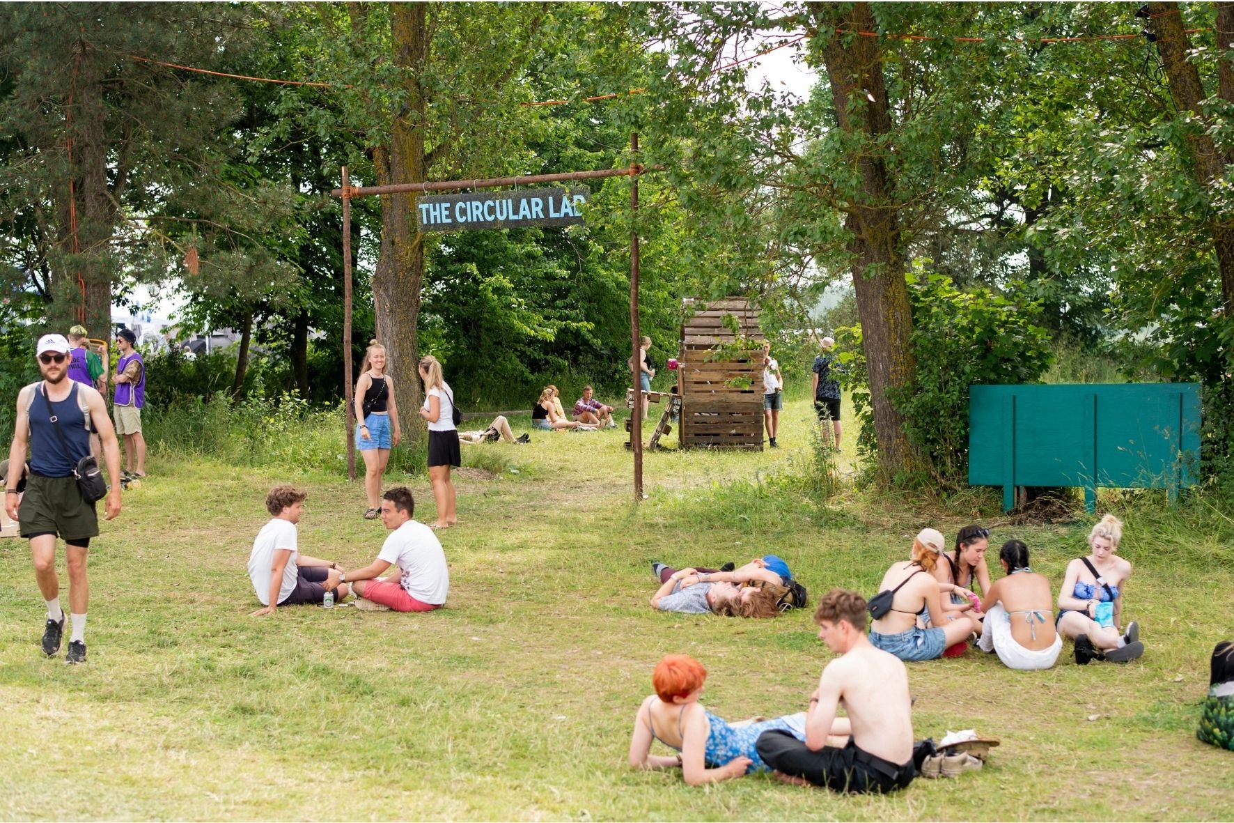 Mange unge sidder foran indgangen til The Circular Lab på Roskilde festival, hvor der foretages forsøg der skal hjælpe med at skabe en bæredygtig fremtid