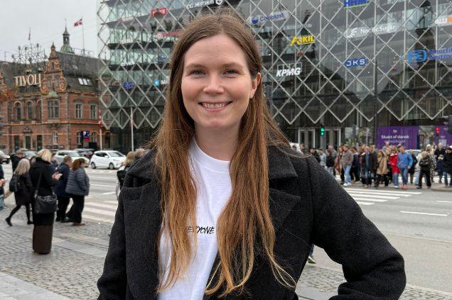 Ellen på Rådhuspladsen i København med de mange virksomhedslogoer bag sig. Hun er særligt inspireret af Coloplast.