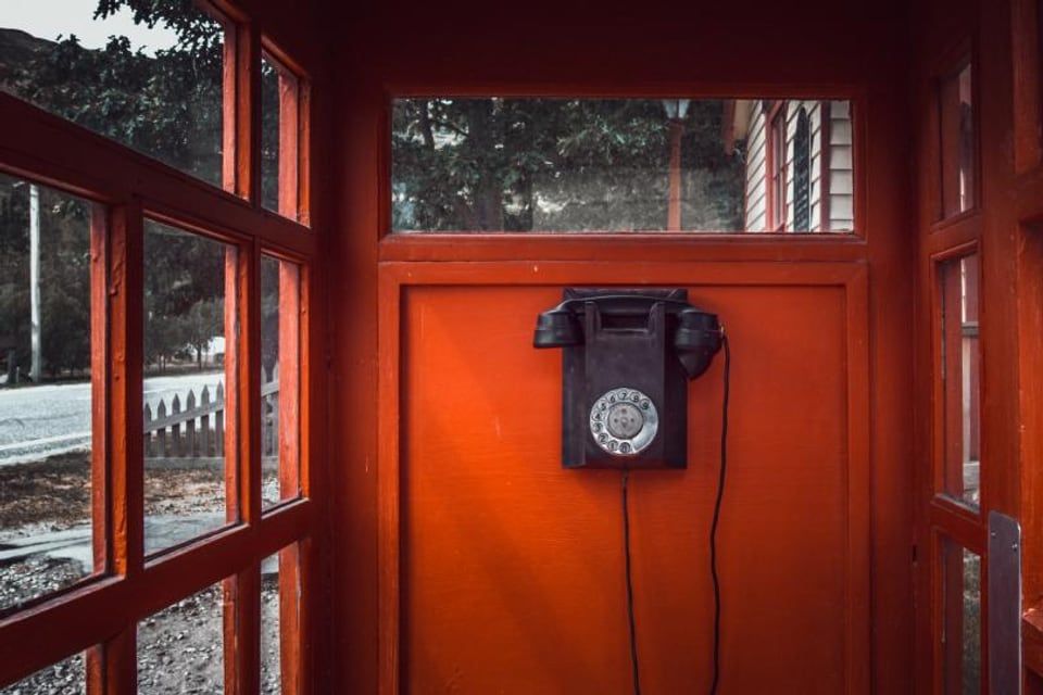 Un téléphone ancien dans une cabine aux boiseries rouges