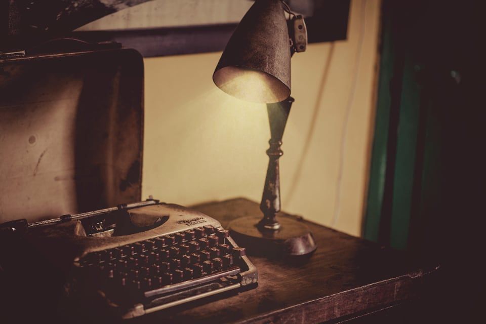 Une machine à écrire ancienne éclairée par une lampe de bureau