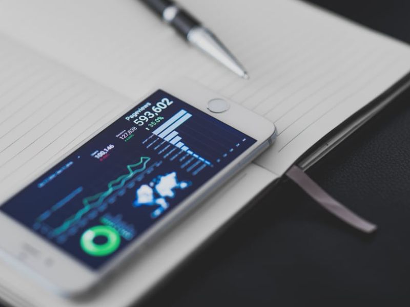 Un smartphone affichant des graphiques, posé sur un carnet