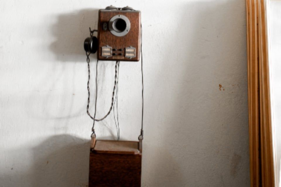 Un téléphone mural ancien, en bois, sur un mur blanc