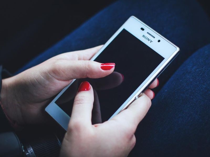 Des mains aux ongles rouges tenant un smartphone