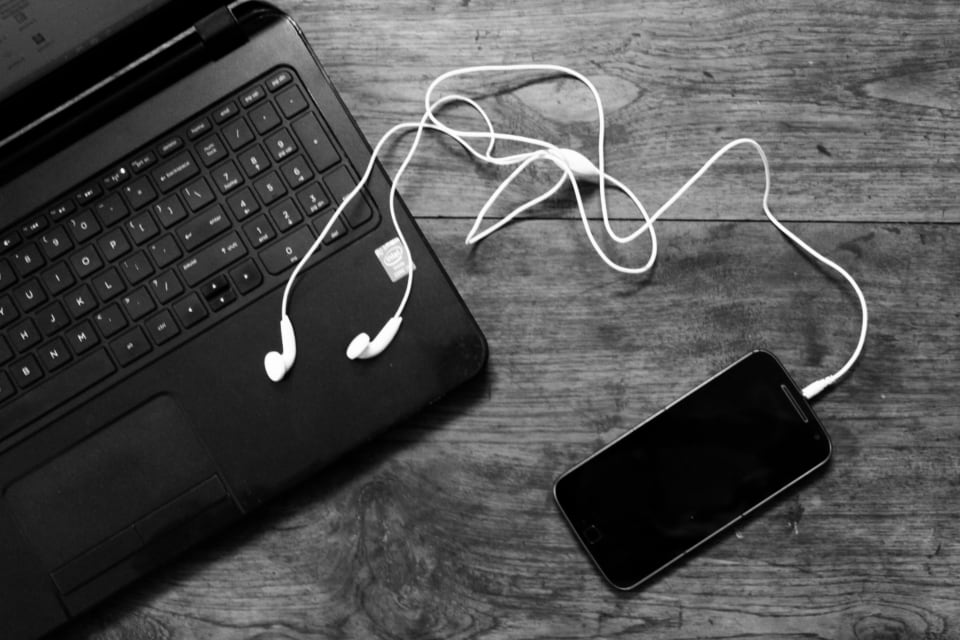 Un ordinateur portable, des écouteurs et un smartphone posés sur une table