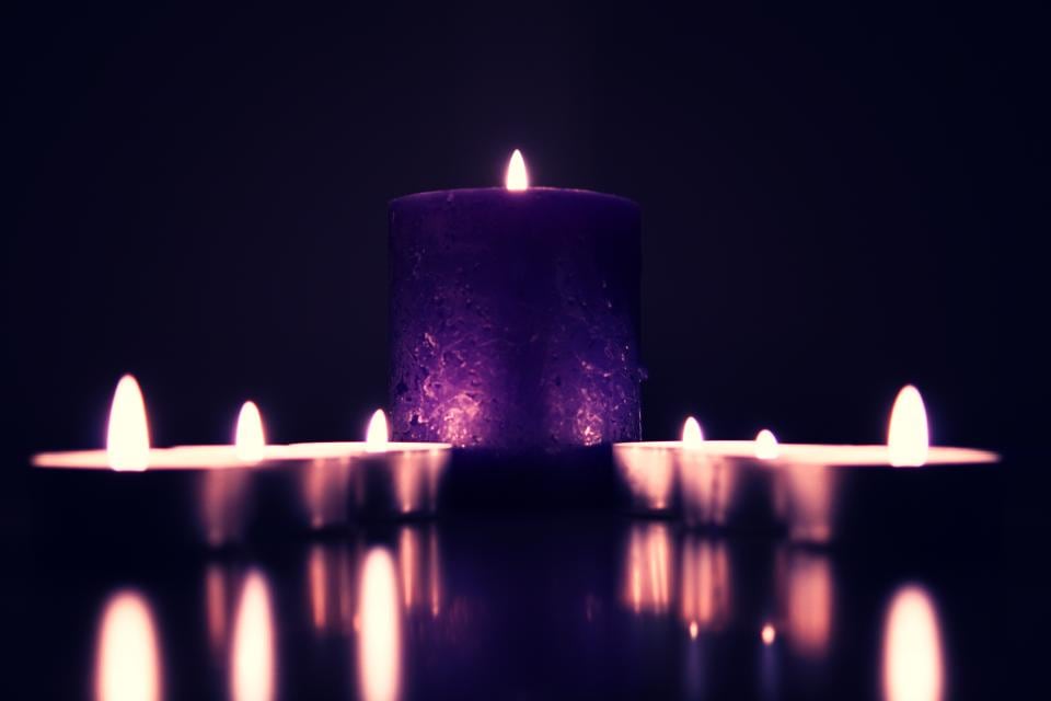 Des bougies allumées dans une lumière violette