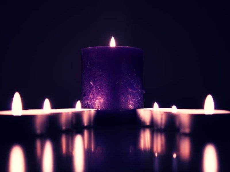 Des bougies allumées dans une lumière violette