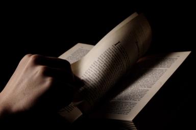 Image of a book with hand turning a page 
