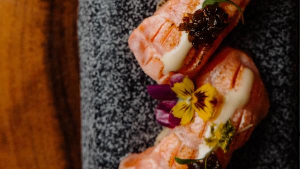 Thinly sliced salmon tiradito topped with yellow ají emulsion and cilantro leaves at Carnal Barcelona restaurant